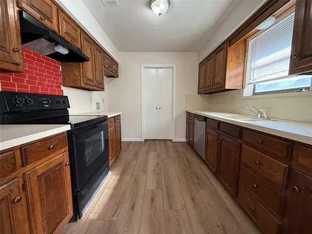 a kitchen with stainless steel appliances granite countertop wooden cabinets a stove top oven a sink and dishwasher