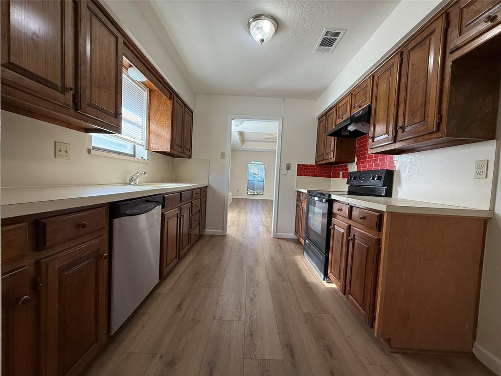 526 Post Oak Lane Allen, TX 75002 - Photo 7 of 18 a kitchen with stainless steel appliances granite countertop wooden cabinets a refrigerator a stove a sink and dishwasher with wooden floor