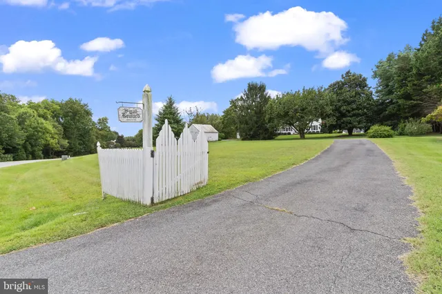 an aerial view of a residential houses with outdoor space and trees all around
