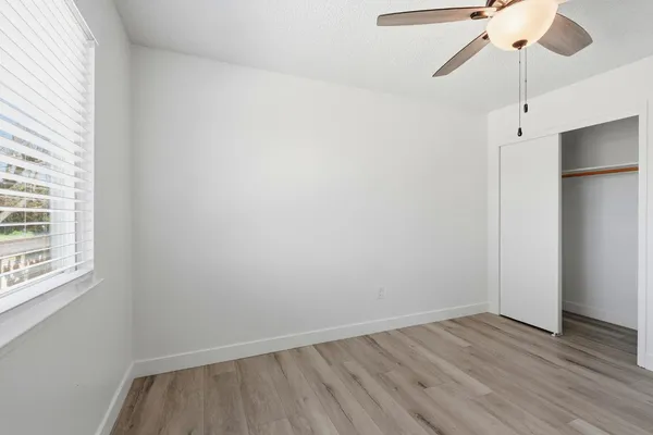 a view of an empty room with wooden floor and a window