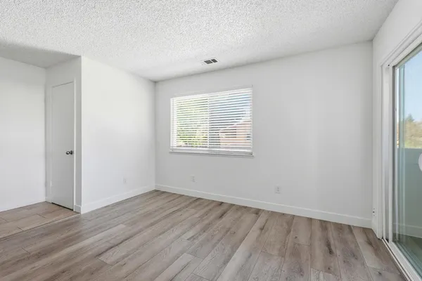 an empty room with wooden floor and windows