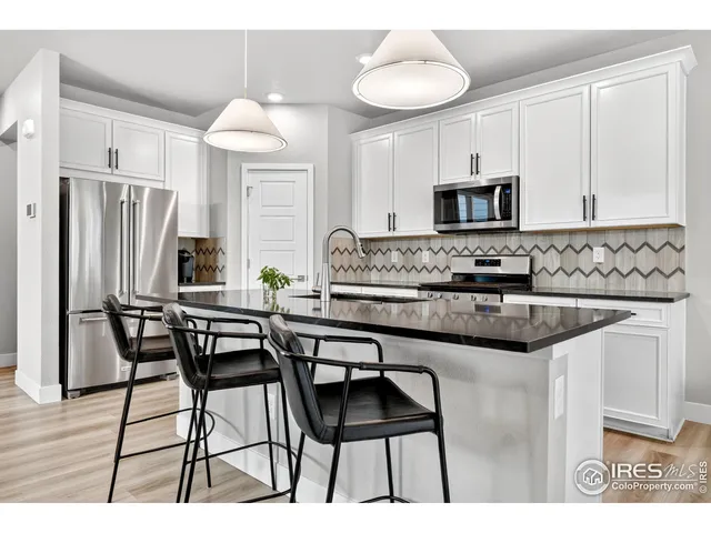 a kitchen with stainless steel appliances kitchen island granite countertop a table chairs sink and cabinets