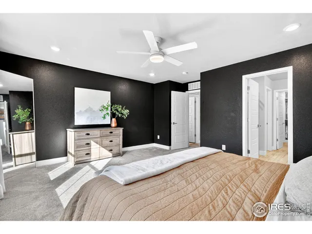 a bedroom with a large bed a flat tv screen and large dresser