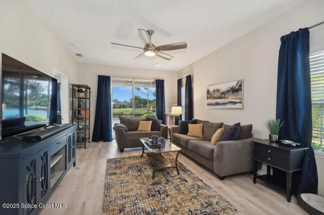 a living room with furniture a ceiling fan and a flat screen tv