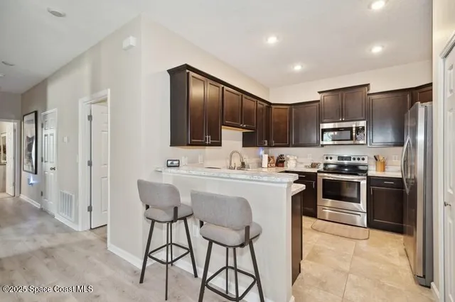 a kitchen with stainless steel appliances granite countertop a stove top oven a sink dishwasher a refrigerator and a oven with wooden floor