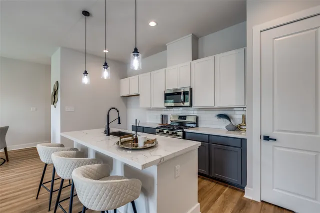 a kitchen with kitchen island granite countertop a sink a stove a dining table and chairs