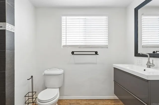 a bathroom with a toilet a sink a vanity and a window