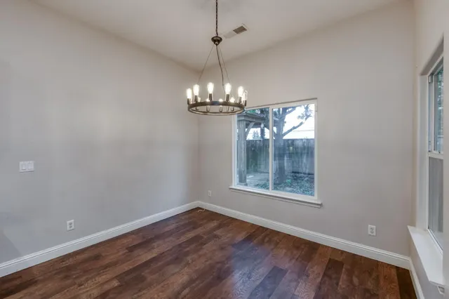 a view of a room with wooden floor chandelier and window
