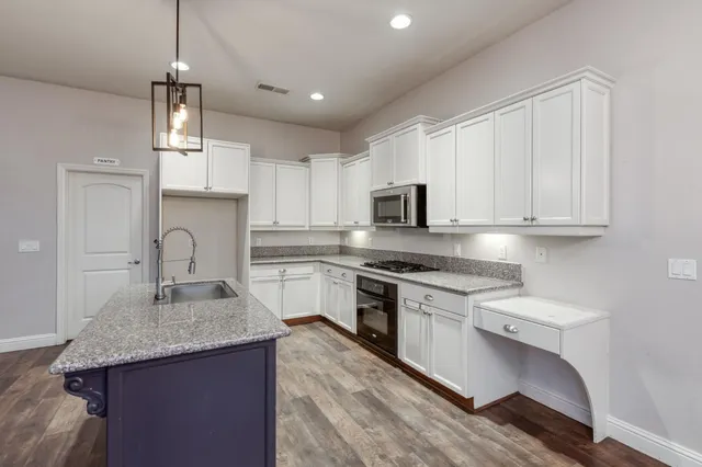 a kitchen with granite countertop white cabinets and stainless steel appliances