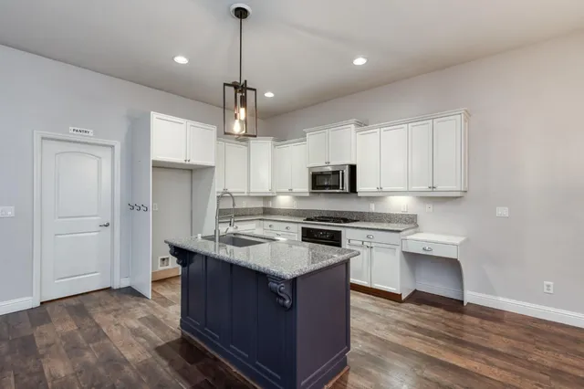 a kitchen with granite countertop white cabinets and stainless steel appliances