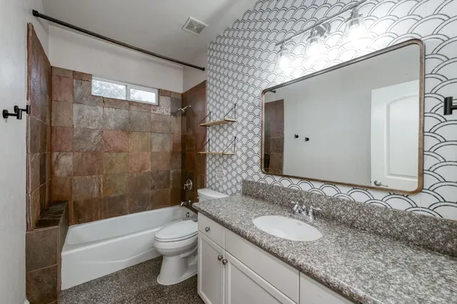 a bathroom with a granite countertop sink toilet and shower