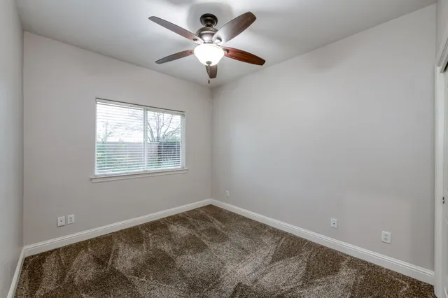an empty room with a chandelier fan and windows