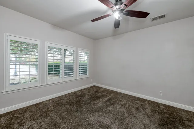 an empty room with a window and a ceiling fan