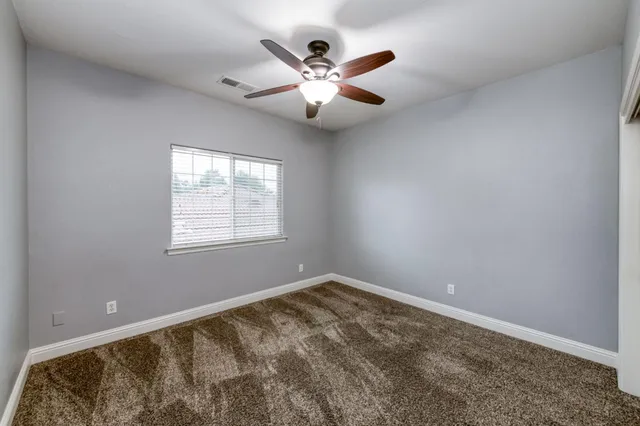 an empty room with a window and a ceiling fan