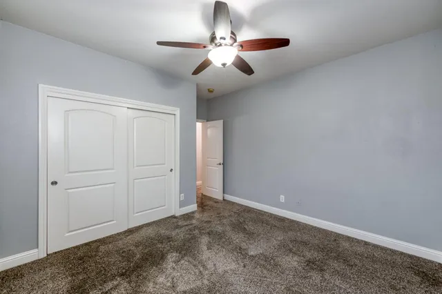 a view of an empty room with chandelier fan