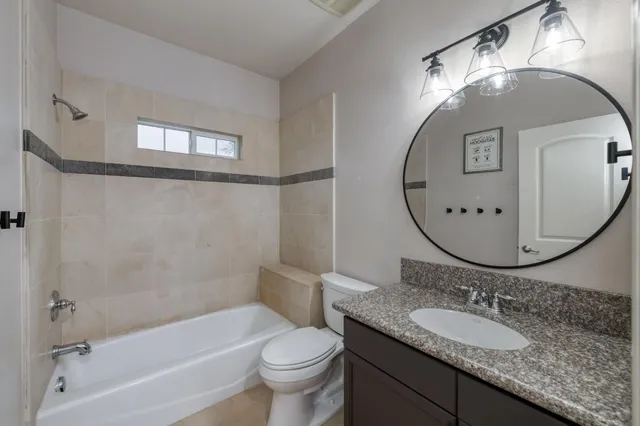 a bathroom with a granite countertop sink a toilet and a mirror