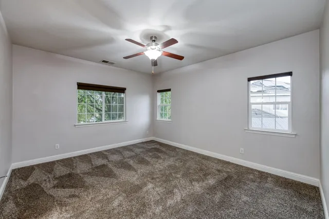 an empty room with windows and fan