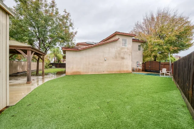 a backyard of a house with wooden fence and large trees