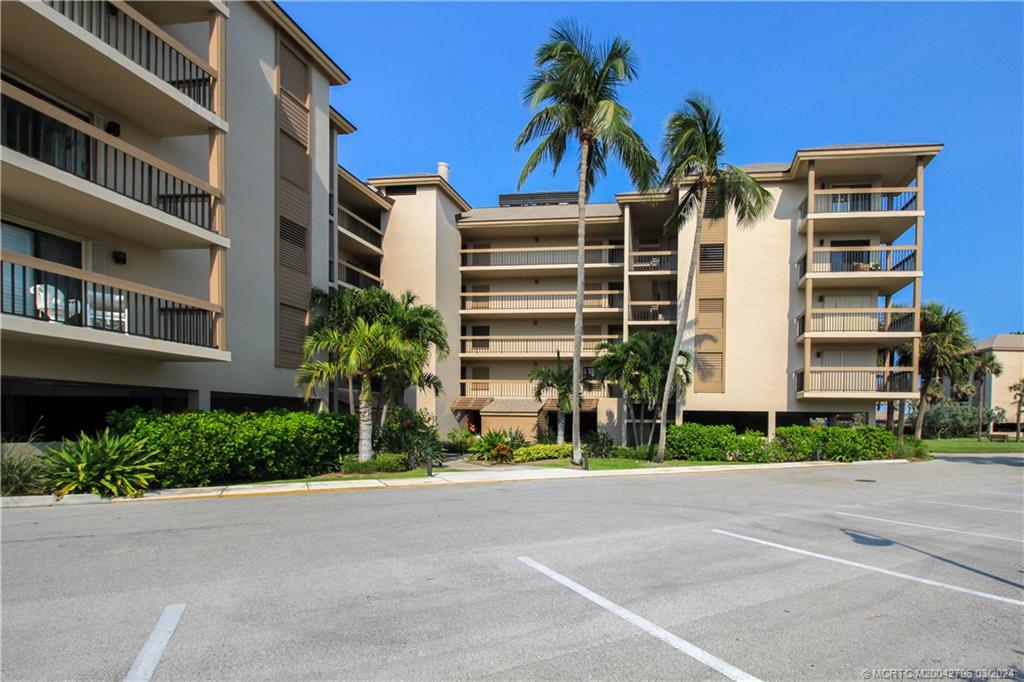 2641 Northeast Ocean Boulevard, Unit 101 Stuart, FL 34996 - Photo 2 of 41 a front view of multi story residential apartment building with yard and parking