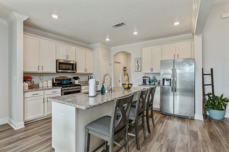 221 Sweet Tea Lane Freeport, FL 32439 - Photo 12 of 55 a kitchen with stainless steel appliances granite countertop a refrigerator a stove top oven a sink dishwasher a dining table and chairs with wooden floor