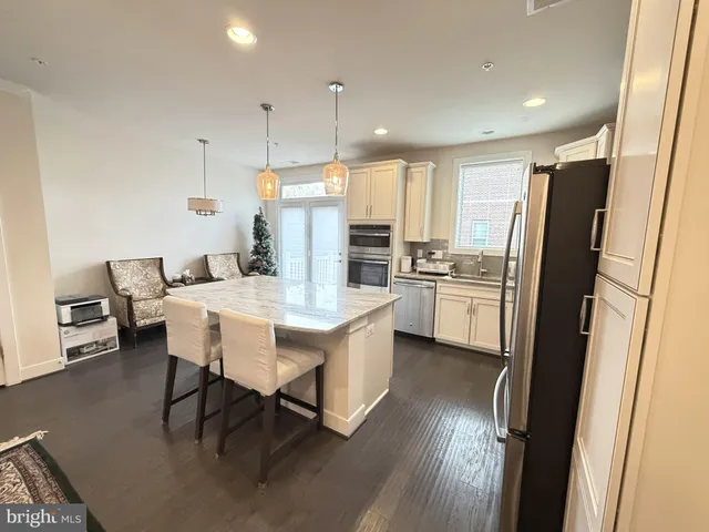 a kitchen with stainless steel appliances a dining table chairs sink refrigerator and microwave