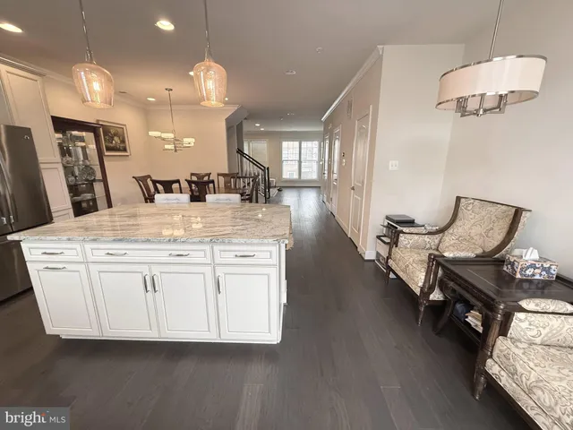 a dining hall with granite countertop wooden floor white cabinets and a chandelier