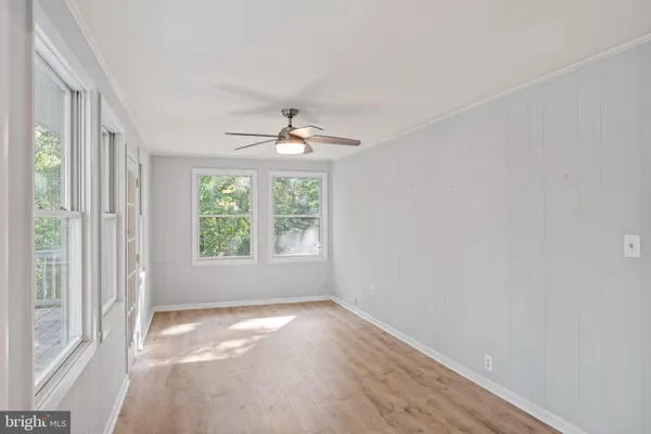 a view of empty room with wooden floor and fan