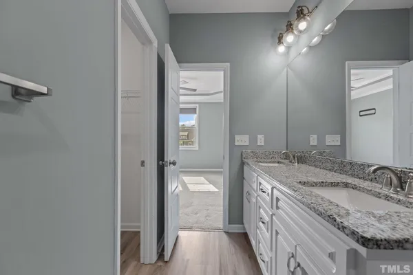 a bathroom with a granite countertop double vanity sink and a mirror