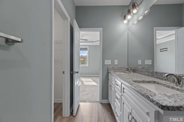 a bathroom with a granite countertop double vanity sink and a mirror