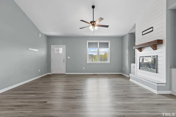 a view of an empty room with a window and wooden floor