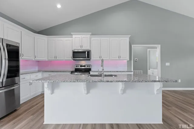 a kitchen with stainless steel appliances granite countertop a sink a stove a refrigerator a microwave and cabinets