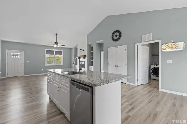 a kitchen with granite countertop a sink cabinets and wooden floor