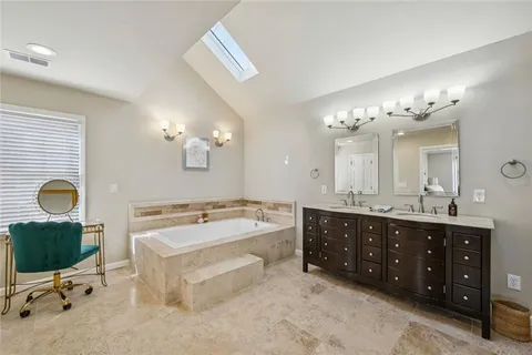 a spacious bathroom with a double vanity sink a mirror a bathtub and a window