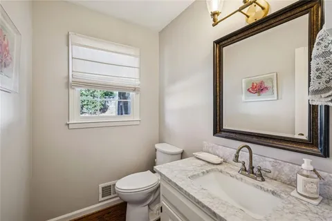 a bathroom with a granite countertop toilet a sink and a mirror