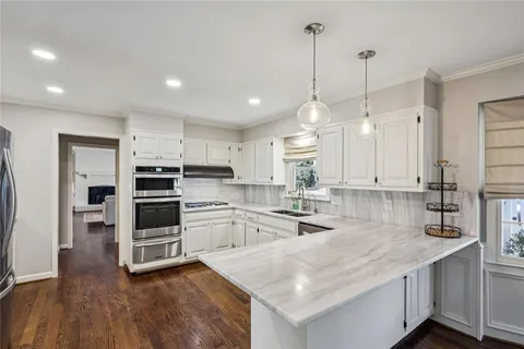 a kitchen with stainless steel appliances kitchen island granite countertop a stove a sink and a refrigerator with wooden floor