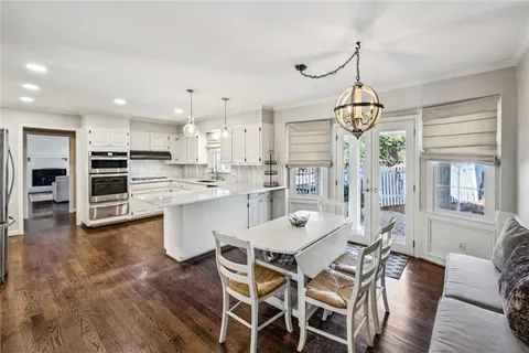 a view of a dining room and livingroom with furniture wooden floor a chandelier