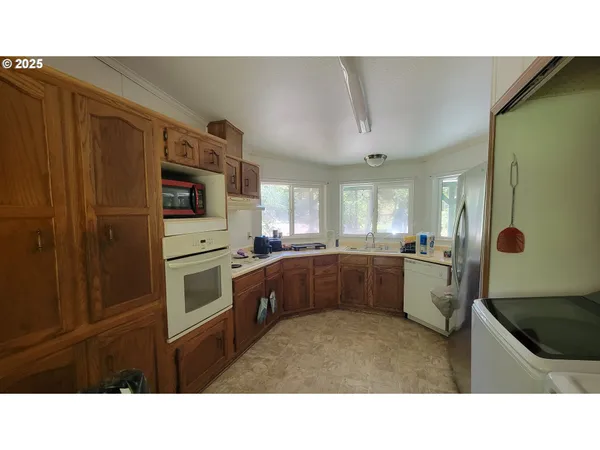 a kitchen with stainless steel appliances kitchen island granite countertop a refrigerator oven a sink with dishwasher and cabinets
