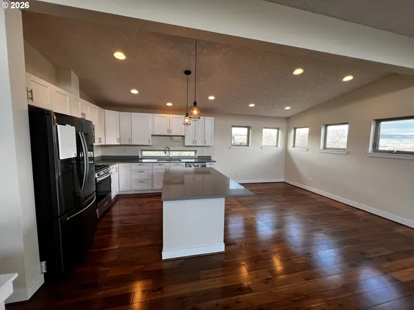 a large kitchen with stainless steel appliances refrigerator a stove top oven a dining table and chairs with wooden floor