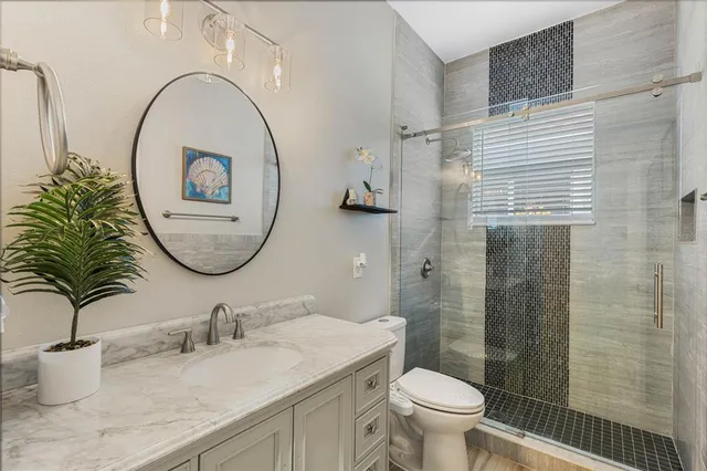 a bathroom with a granite countertop toilet a sink and a mirror