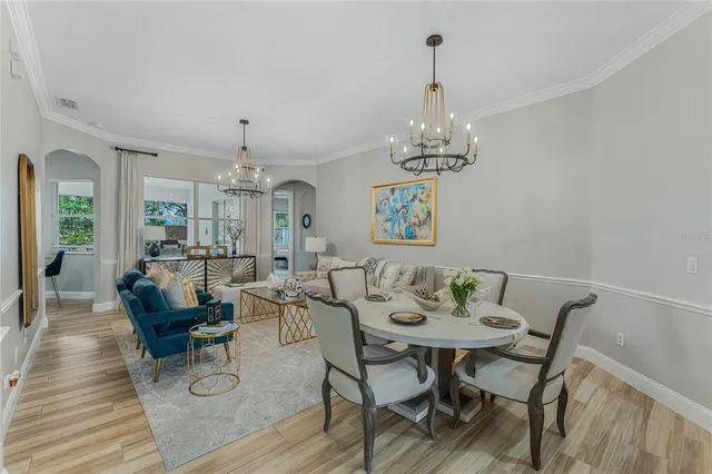 a view of a dining room with furniture a chandelier and wooden floor