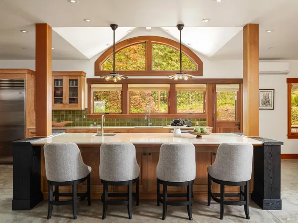 a dining hall with stainless steel appliances a stove a dining table and chairs with wooden floor