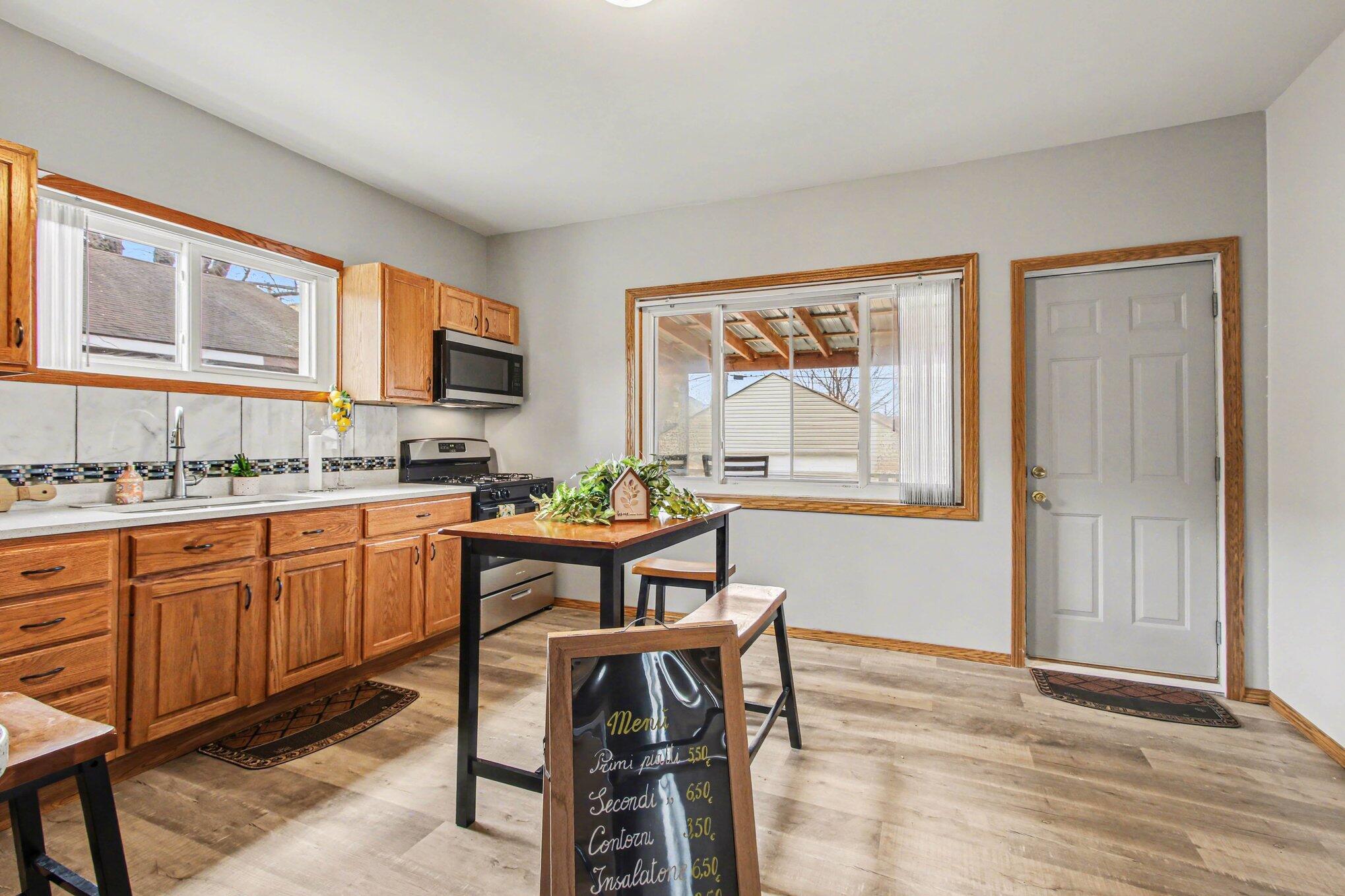 5962 Park Place Hammond, IN 46320 - Photo 7 of 20 a kitchen with stainless steel appliances granite countertop a stove top oven a sink dishwasher a dining table and chair with wooden floor