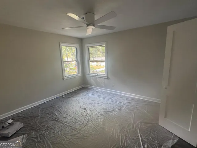 an empty room with windows and fan