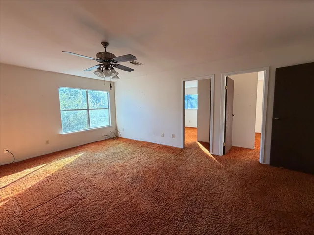 an empty room with windows and ceiling fan