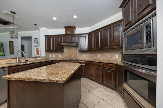 a kitchen with granite countertop wooden cabinets and stainless steel appliances