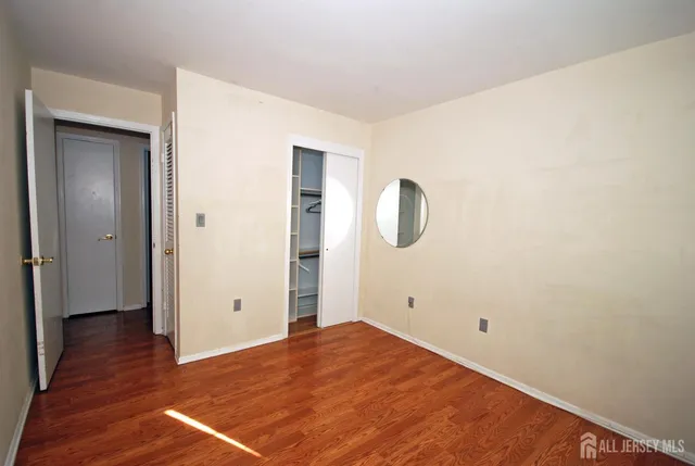 an empty room with wooden floor and mirror