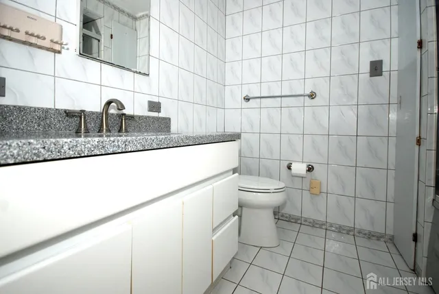 a bathroom with a granite countertop toilet a sink and mirror