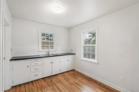 a room with granite countertop white cabinets and window