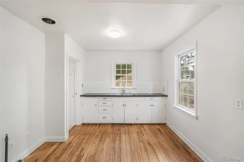 a kitchen with granite countertop white cabinets and wooden floor
