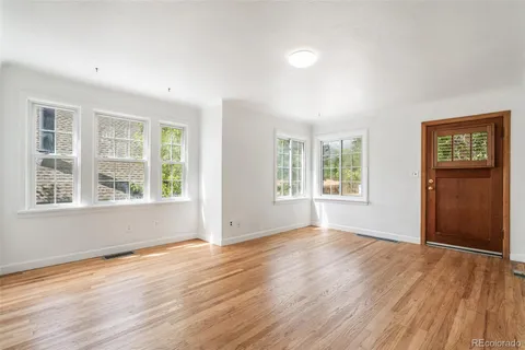 a view of an empty room with wooden floor and windows